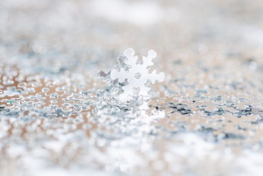 Christmas decoration of silver confetti snow flake against white background with nice boke. Close up confetti with shallow DOF