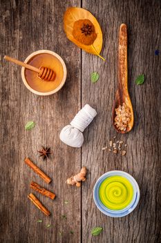 Composition of nature spa ingredients on the dark wooden table. Spa and wellness with honey ,herbal compress ball,turmeric,cinnamon powder ,cinnamon sticks ,aromatic oil and star anise.