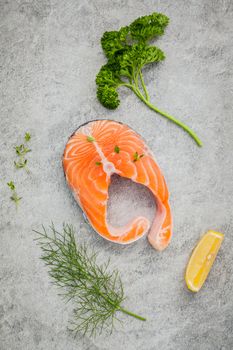 Fresh salmon fillet slice on dark stone background with herbs fennel ,sage ,rosemary thyme,parsley and lemon propose  for cooking . Healthy food concept.