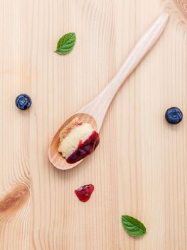 Composition of blueberry cheesecake in wooden spoon with fresh mint leaves and ripe blueberry on wooden background. Food background flat lay.