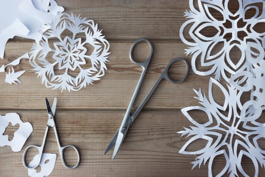 handmade paper snowflakes and scissors on table