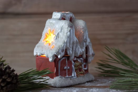 winter house candle and Christmas tree branches on wooden table