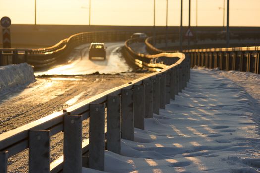 winter road with fence, distant car, sunset