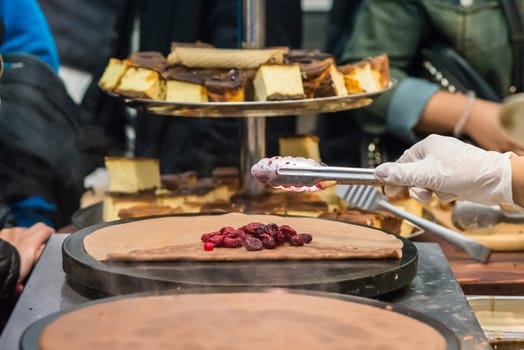 hand puts cherry on chocolate pancake outdoors