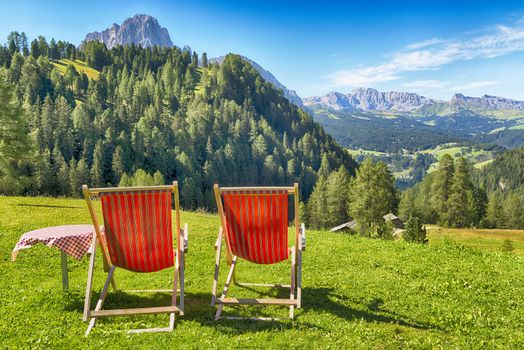 deck chairs and table on the lawn overlooking the mountains and the valley in summer