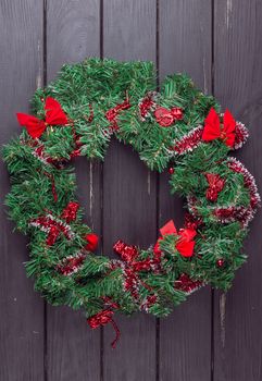 Christmas wreath on a rustic wooden black front door.