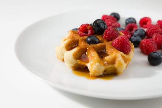 Waffles with fresh ripe berries over a white plate