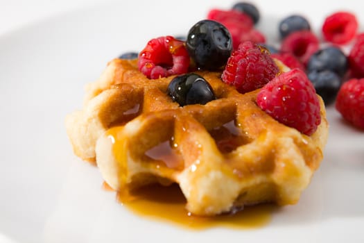 Close-up of waffles with fresh ripe berries on a white background