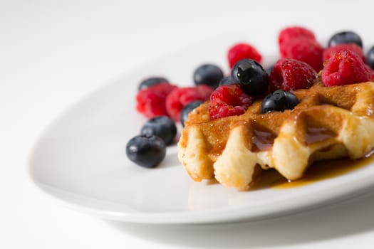 Close-up of waffles with berries over a white plate