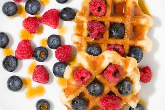 Close-up of waffles with berries and maple syrup seen from above