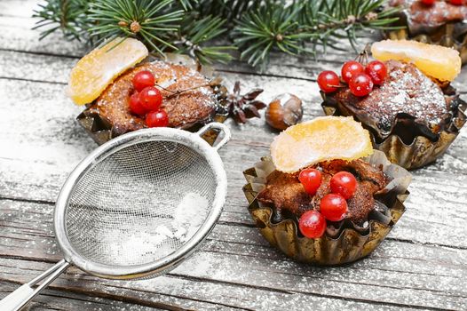 Chocolate Christmas muffins,sieve the powder on background with branch of Christmas tree