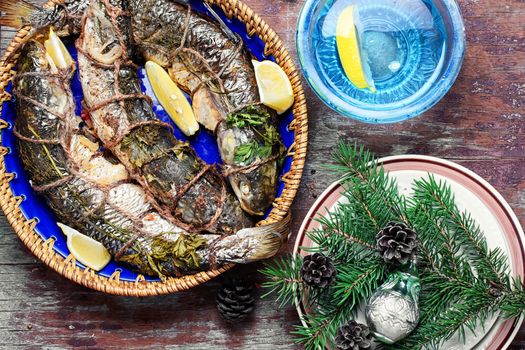 Christmas table with dish of roasted fish and Christmas tree decorations