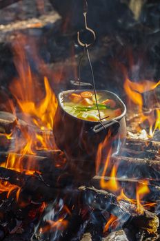 vegetable soup in old tourist pot at fire place Summer trekking activity