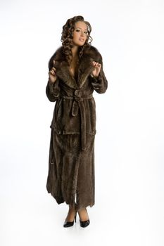 Young attractive woman in a fur coat on an isolated studio background