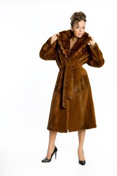 Young attractive woman in a fur coat on an isolated studio background