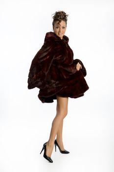 Young attractive woman in a fur coat on an isolated studio background