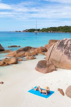 Woman wearing black bikini and beach hat, sunbathing at Anse Lazio beach on Praslin Island, Seychelles. Summer vacations on picture perfect tropical beach concept.