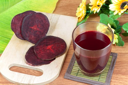 Fresh slices red beetroot and beetroot fruit juice in glass a wood background