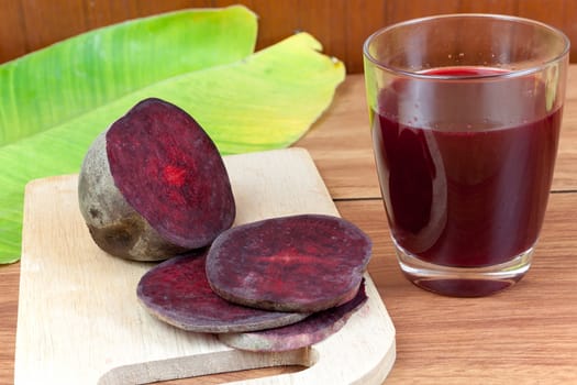 Fresh slices red beetroot and beetroot fruit juice in glass a wood background