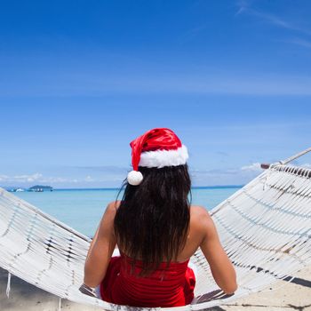Woman in hammock on tropical beach celebrating Christmas