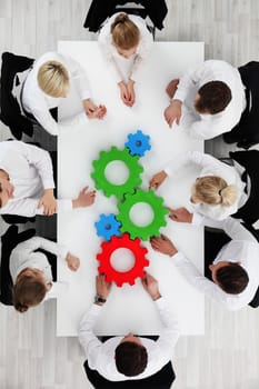 Business team sitting around the table with cogs, teamwork concept