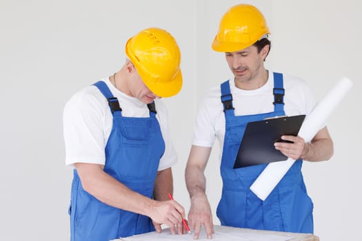 Team of builders with construction plan indoors