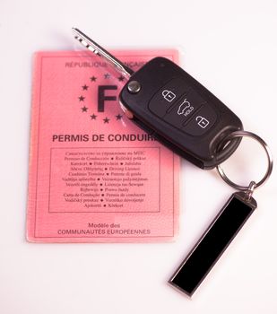 Car keys and drivers license on white background, France
