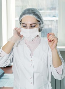 Woman scientist in a white protective clothing preparing for the experiments in the laboratory