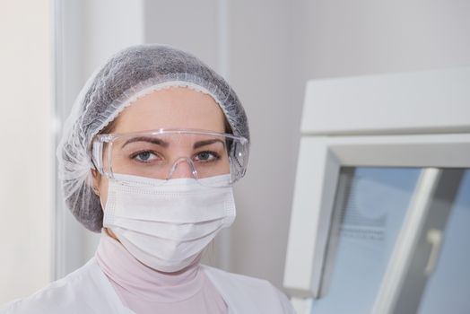 Woman scientist in a white protective clothing preparing for the experiments in the laboratory looking directly