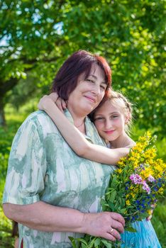 granddaughter hugs her grandmother in the garden