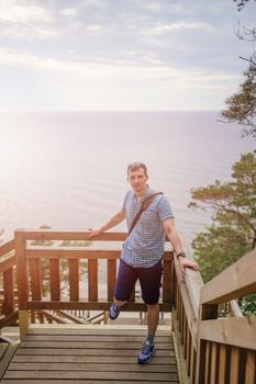 young man sitting on the wooden stairs in park and smiling