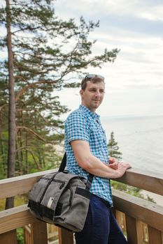 young man sitting on the wooden stairs in park and smiling