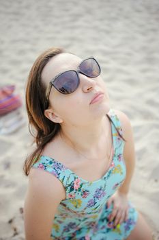 Young attractive brunette woman on a beach wearing dress