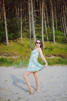 Young attractive brunette woman on a beach wearing dress