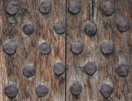 An old and rough wood surface with rusty metal round nails.