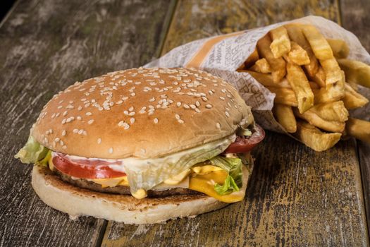 Hamburger and fried potato on an old wooden desk