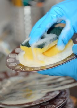 Close up hands with gloves of woman washing dishes