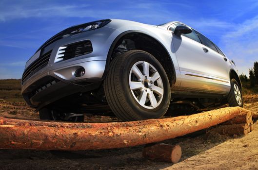 SUV overcomes the obstacle built from wooden logs