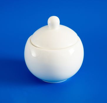 White sugar bowl with lid on a blue background