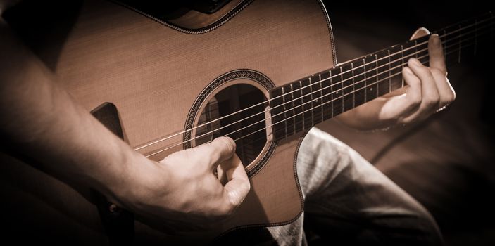 Close up of hands on the strings of a guitar, France
