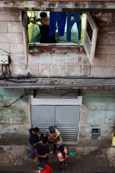 Havana, Cuba - 27 January 2016: Woman extending the clothes at the window of her house and people walking on the street at the neighborhood of Habana Vieja in Havana on Cuba