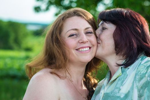 happy mom kisses daughter in the garden