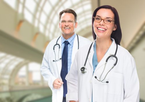 Two Male and Female Doctors or Nurses Standing Inside Hospital Building.