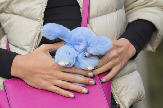 Hands girl on the stylish pink bag keep fur toy rabbit