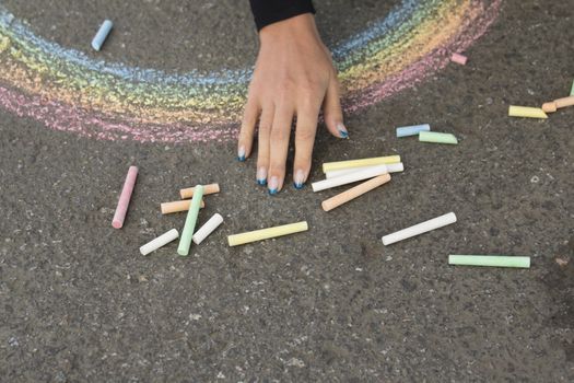 Hand draws with crayons colored Rainbow girl on the pavement
