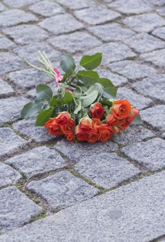 A bouquet of bright coral Roses on stone pavement in the city