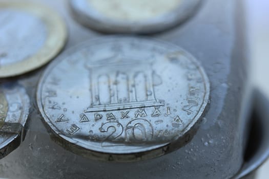 Frozen Assets: Greek euro and Drachme coins in ice