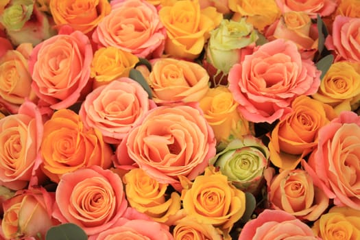 Yellow, orange and pink roses in a floral arrangement at a wedding