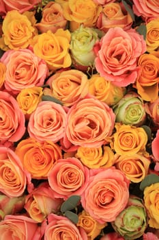 Yellow, orange and pink roses in a floral arrangement at a wedding