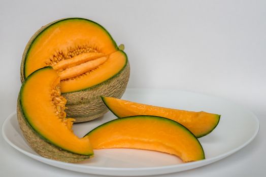cut cantaloupe with slices on white background